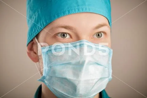 Male surgeon in mask looking at camera on grey background, close up Stock Photos