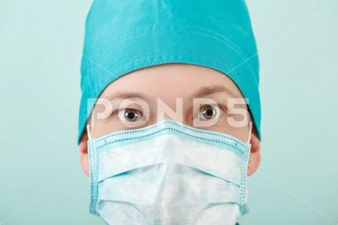 Male surgeon in mask looking at camera on blue background, close up Stock Photos