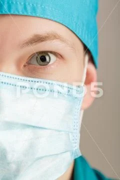 Male surgeon in mask looking at camera on grey background, close up Stock Photos