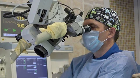 A male surgeon performs a microscopic operation on a patient's ENT organs using Stock Footage 109410918