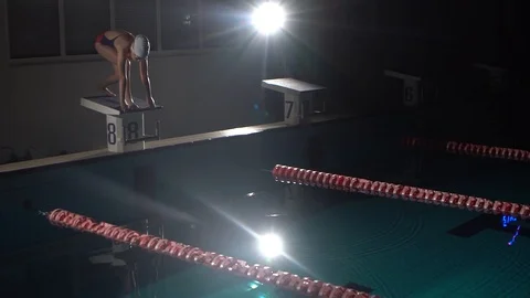 Male swimmer jumps off starting block and start swims in pool. Professional Stockbeeldmateriaal 116689953