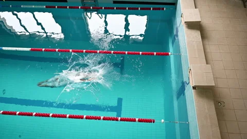 Male swimmer performs powerful jump into pool from edge seen from above Stock Footage 346550924