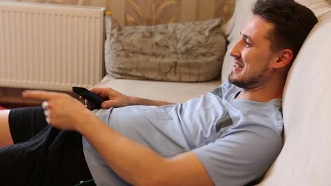 Male switch TV channels while sitting on the couch Stock Footage 72581349