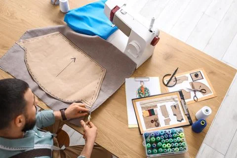 Male tailor cutting pattern on table in atelier, top view Stock Photos