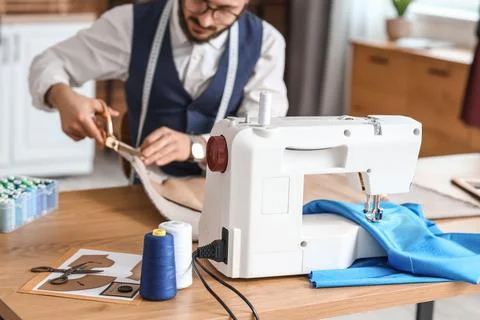 Male tailor cutting pattern at table in atelier Stock Photos