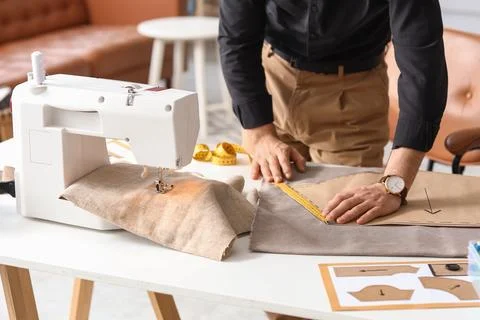 Male tailor measuring pattern at table in atelier Stock Photos