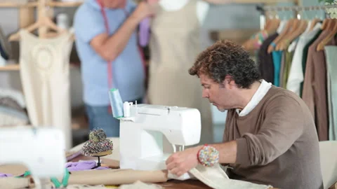 Male tailor is working at a sewing machine against the background of a tailor Stock Footage 316581700