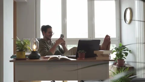 Male taking a study break and checking his phone with feet on the table Stock Footage 162106707