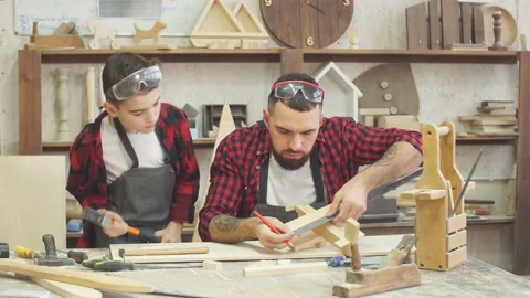 Male teacher and his male pupil making by hand a DIY wooden toy Stock Footage