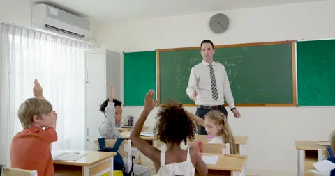 Male teacher asks math question near chalkboard while elementary pupil group Stock Footage 344951550