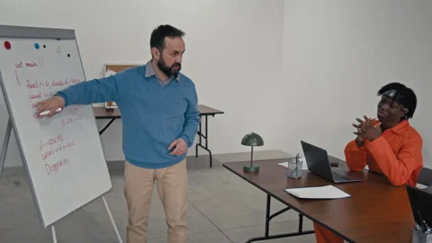 Male Teacher Explaining Coding Theory to Three Multiethnic Inmates in Jail Video stock 314053510