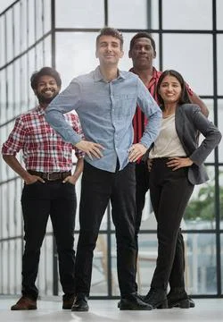 Male teamleader standing with crossed arms with coworkers in background Stock Photos