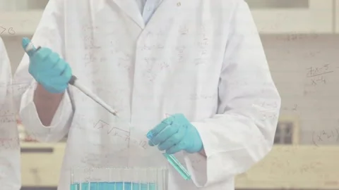 Male tech inserting pipette, transferring blue fluid into tubes with math Stock Footage 330258260