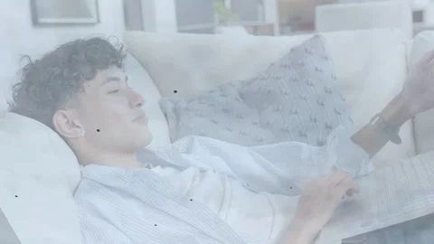 Male tech user on couch tapping laptop and phone causing animated charts syncing Stock Footage 333602797