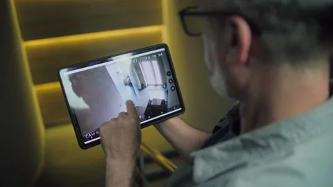 Male technician controls CCTV cameras in modern office using tablet computer Stock Footage 280837536