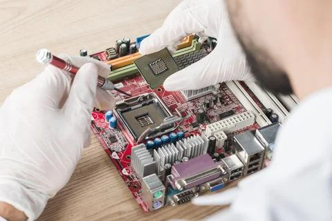 Male technician inserting chip computer motherboard wooden desk Resolution and Stock Photos