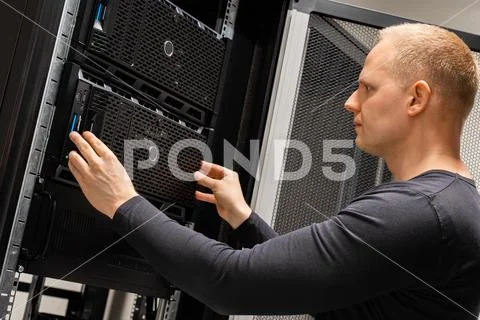 Male Technician Installing Servers In Enterprise Datacenter for Cloud Hosting Stock Photos