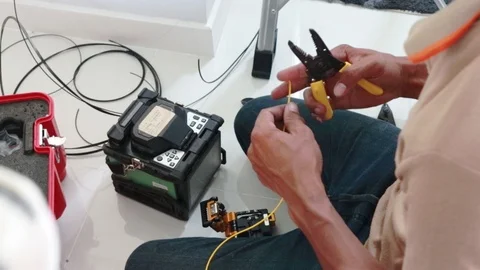 Male technician peeling protective layer off from a fiber optic cable Vidéo 102189767