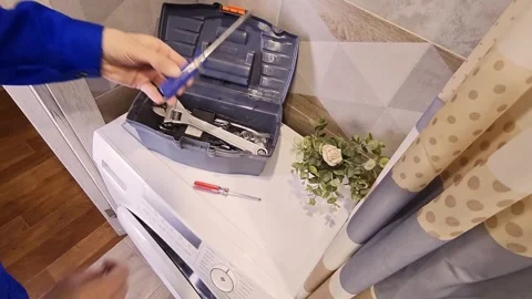 Male technician prepares tools from oolbox on washing machine Stock Footage 336480061