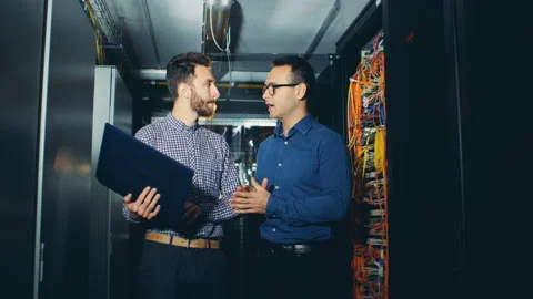 Male technician in a server room is getting instructed by his colleague Video stock 99092131
