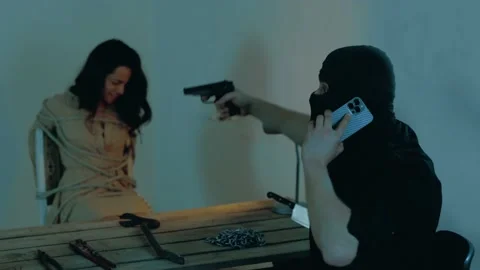 Male terrorist demanding a ransom while speaking on the phone, pointed a gun at Stock Footage 238987437