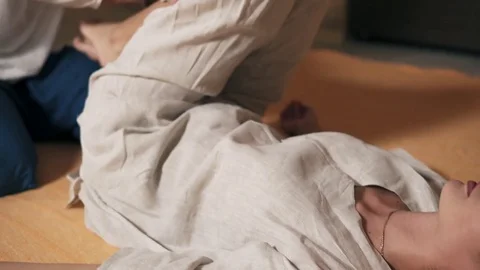 Male thai massagist is treating young woman's back holding her legs and turning Stock Footage