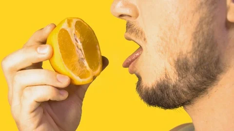 Male Tongue Licking Sliced Orange Imitating Cunnilingus on Yellow Background Stock Footage