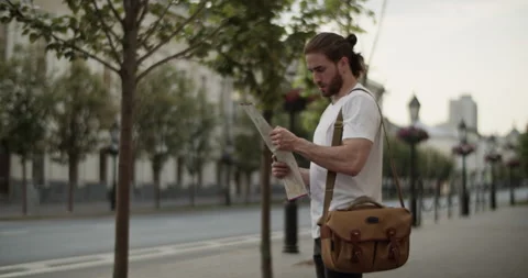 Male tourist checking map while standing on city street Stock Footage 249785549