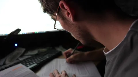 Male trader analyzing stock graphs on multiple computer screens and making notes Stock Footage 309299665