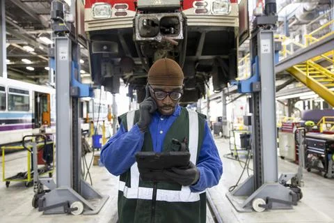 Male transit engineer using digital tablet in maintenance facility Stock Photos