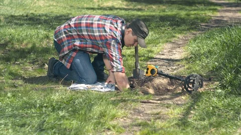 Male treasure hunter pulls out old coins found on the field with metal detector Stock-Footage 89865501