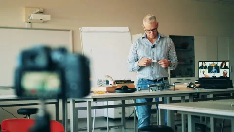 Male tutor is conducting an e-class which is being filmed live. Remote education Stock Footage 140726014