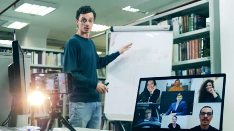 Male tutor teaching his class remotely using a whiteboard Stock Footage 145637633