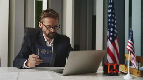 Male U.S. embassy officer checking passport data on laptop, approval process Stock Footage 327784657