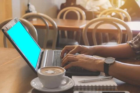 Male using a computer with coffee cup on wooden table. Stock Photos