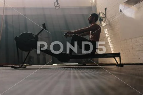 Male using rowing machine at fitness club Stock Photos
