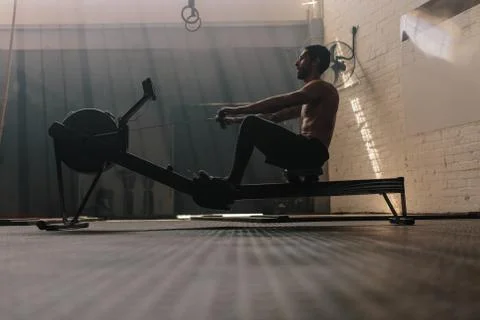 Male using rowing machine at fitness club Stock Photos
