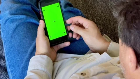 Male using Smartphone with Green Mock-up Screen green chroma key screen on cozy Stock-Footage 336249554