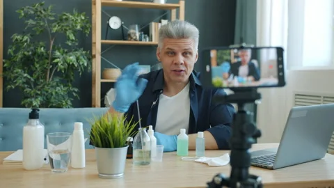 Male vlogger recording tutorial about making hand sanitizer using smartphone Stock Footage 131273360