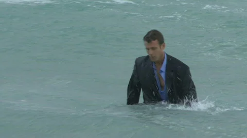 Male walking out of the ocean in suit Stock Footage