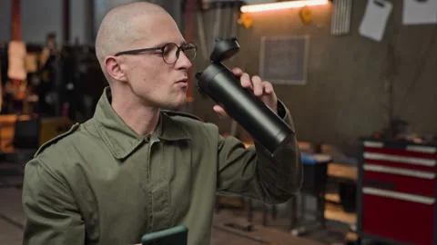Male Welder Drinking from Thermos While Checking Smartphone Stock Footage 342508693