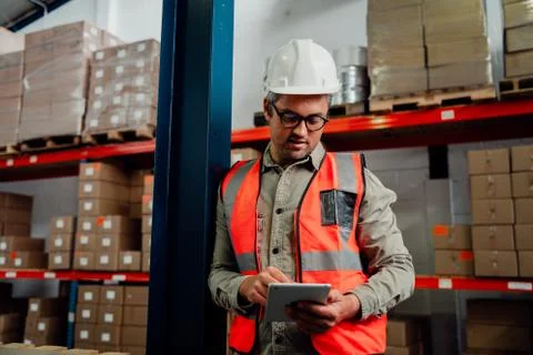 Male worker browsing on digital tablet wearing spectacles while standing in Stock Photos