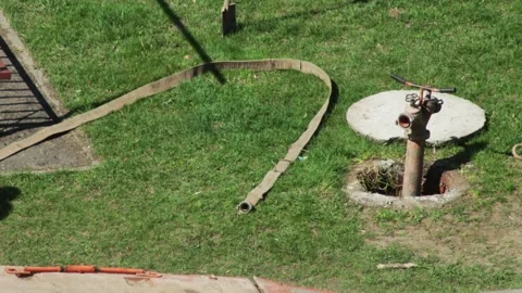 Male worker connects hose to hydrant in sewer well, industry. Copy space for Stock Footage 317807951
