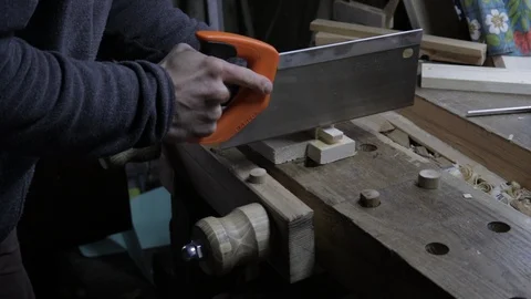 Male worker cutting the pine plank with a hand saw on the wooden workbench in a Vidéo 119669642