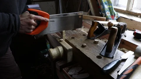 Male worker cutting the pine plank with a hand saw on the wooden workbench in a Vidéo 119670291