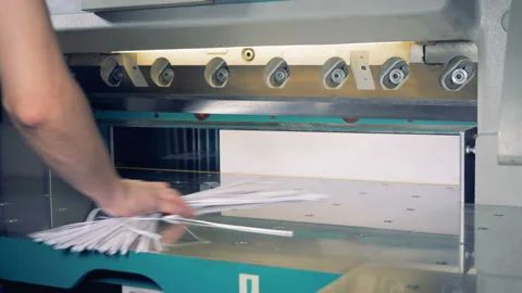 Male worker cutting a stack of paper in a typography. Stock Footage 86413710