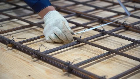Male worker holding bundle of wire, measures distance between rods of rebar Video stock 126357355