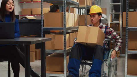 Male worker with impairment taking boxes off of shelves Stock Footage 233745798