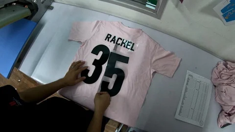 Male worker make adjustment the Name and No on the T-shirt  Stock Footage 106866293
