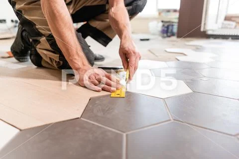 Male worker makes measurements and installing new wooden laminate flooring. The Stock Photos